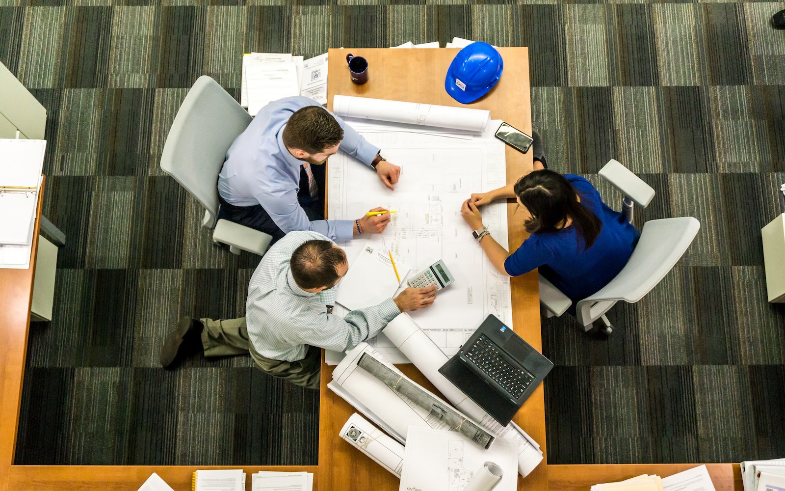 Lazarus Renovation: MEP Plan & Permit Services. Three people sitting at a table covered in paperwork.